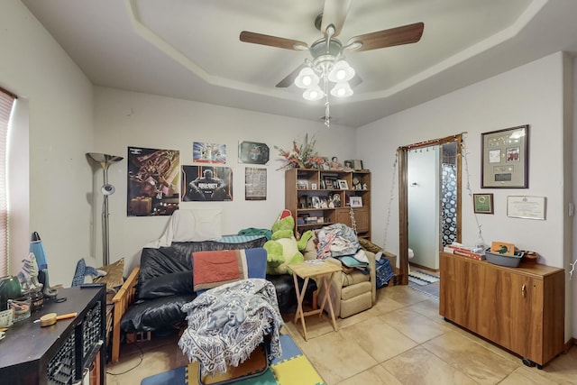 sitting room featuring light tile patterned floors, ceiling fan, and a tray ceiling