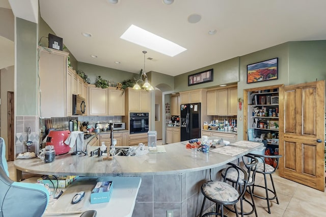 kitchen with pendant lighting, a skylight, black appliances, a kitchen bar, and kitchen peninsula