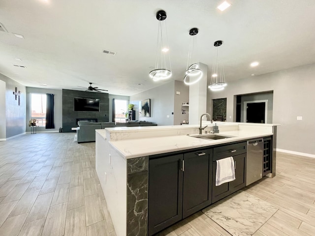 kitchen featuring pendant lighting, sink, a wealth of natural light, and an island with sink