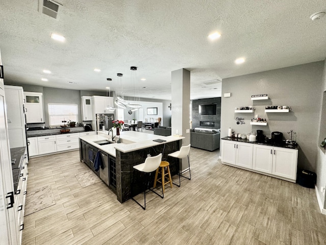 kitchen with a kitchen island with sink, white cabinetry, pendant lighting, and a breakfast bar