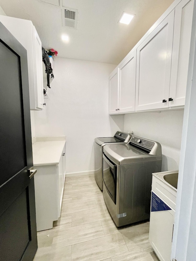 washroom featuring independent washer and dryer and cabinets