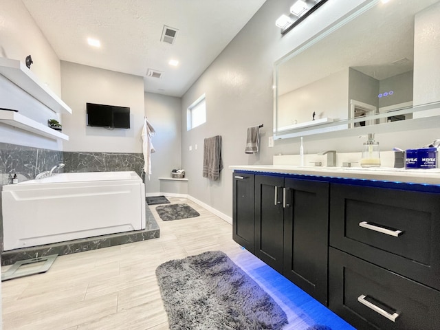 bathroom with a washtub, vanity, and a textured ceiling