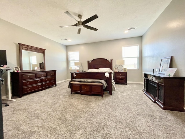 carpeted bedroom with multiple windows, a textured ceiling, and ceiling fan