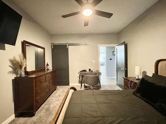 carpeted bedroom featuring a barn door and ceiling fan