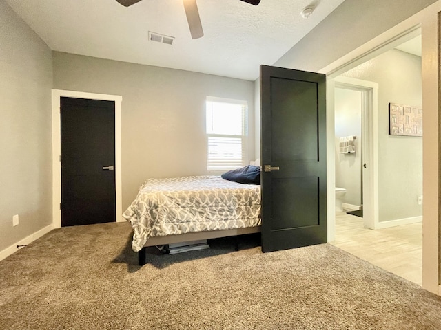 bedroom featuring ensuite bathroom, carpet floors, a textured ceiling, and ceiling fan