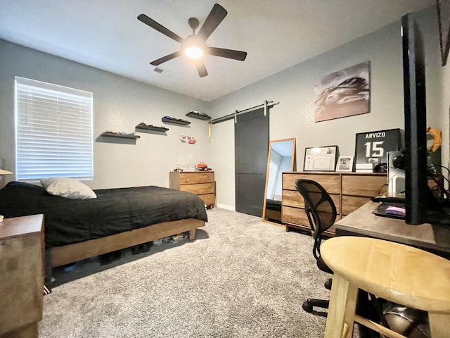 carpeted bedroom with a barn door and ceiling fan