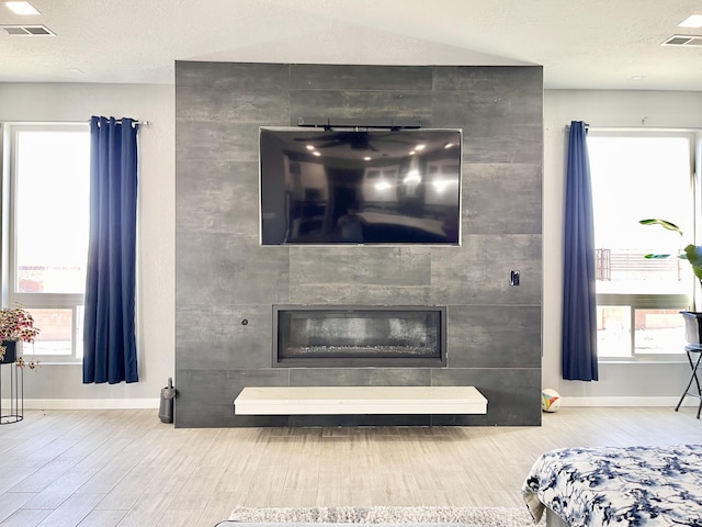 living room with a wealth of natural light, a large fireplace, and hardwood / wood-style floors