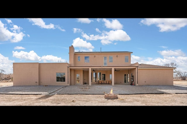 back of property featuring ceiling fan, a fire pit, and a patio area