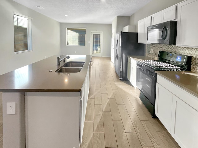 kitchen featuring white cabinets, a kitchen island with sink, sink, and black appliances