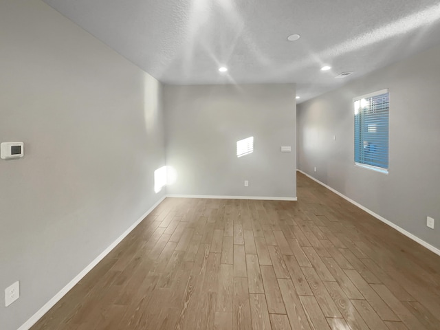 empty room featuring a textured ceiling and light wood-type flooring