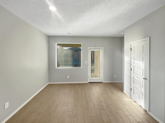 spare room featuring a textured ceiling and light wood-type flooring