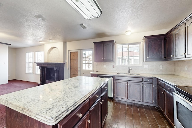 kitchen with a kitchen island, tasteful backsplash, sink, stainless steel appliances, and dark wood-type flooring