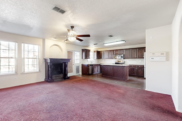 kitchen with a kitchen island, appliances with stainless steel finishes, dark colored carpet, ceiling fan, and dark brown cabinets