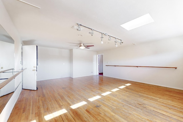 interior space featuring ceiling fan, rail lighting, a skylight, and light wood-type flooring