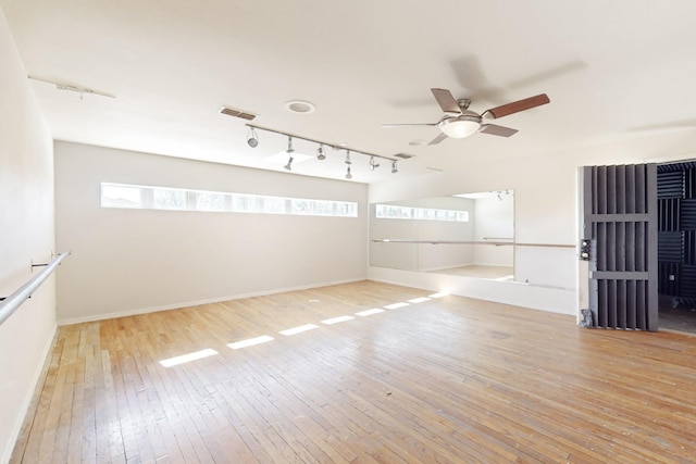 unfurnished room with ceiling fan, track lighting, and light hardwood / wood-style flooring