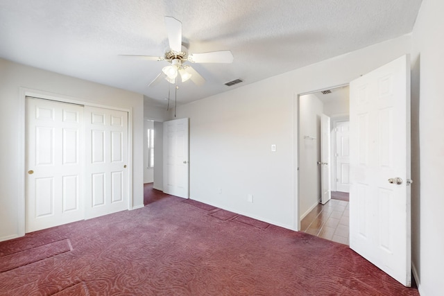 unfurnished bedroom featuring ceiling fan, a closet, a textured ceiling, and carpet flooring