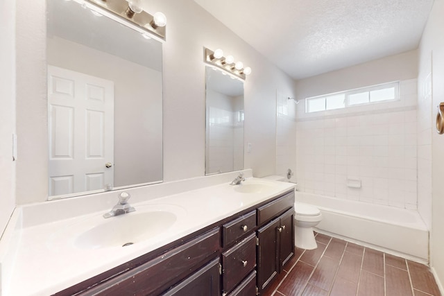 full bathroom with vanity, a textured ceiling, tiled shower / bath combo, and toilet