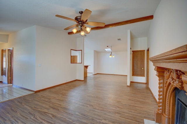 unfurnished living room featuring beam ceiling, wood-type flooring, and ceiling fan