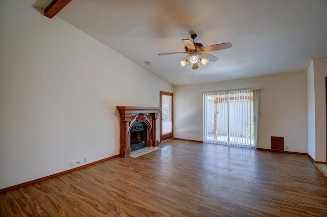 unfurnished living room featuring ceiling fan, hardwood / wood-style floors, a tile fireplace, and vaulted ceiling with beams