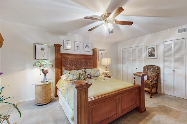 carpeted bedroom with crown molding, ceiling fan, and two closets