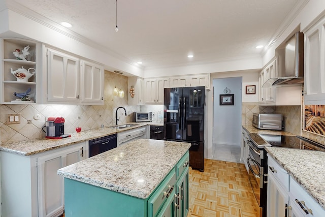 kitchen with tasteful backsplash, white cabinetry, green cabinets, black appliances, and wall chimney exhaust hood