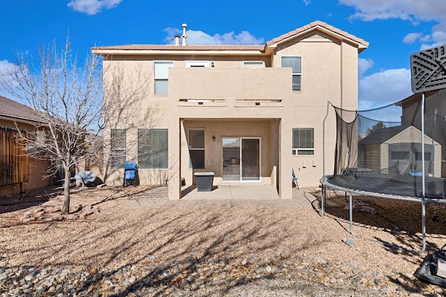 back of property featuring a patio and a trampoline