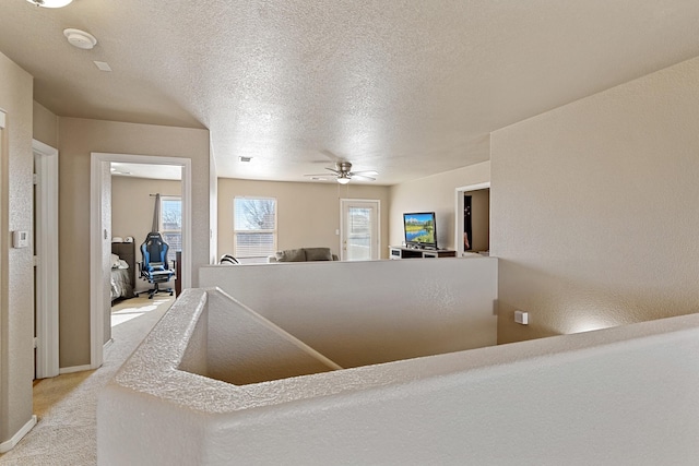 corridor featuring light carpet and a textured ceiling