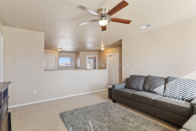 carpeted living room featuring a textured ceiling and ceiling fan