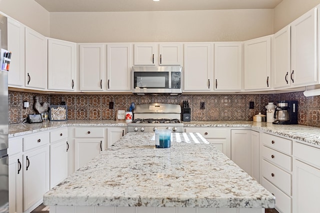 kitchen featuring white cabinetry, stove, and backsplash