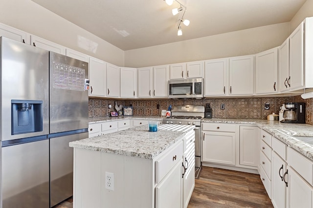 kitchen featuring stainless steel appliances, white cabinetry, a kitchen island, and decorative backsplash