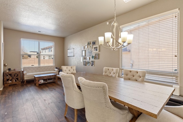 dining space with a notable chandelier, a textured ceiling, and dark hardwood / wood-style flooring