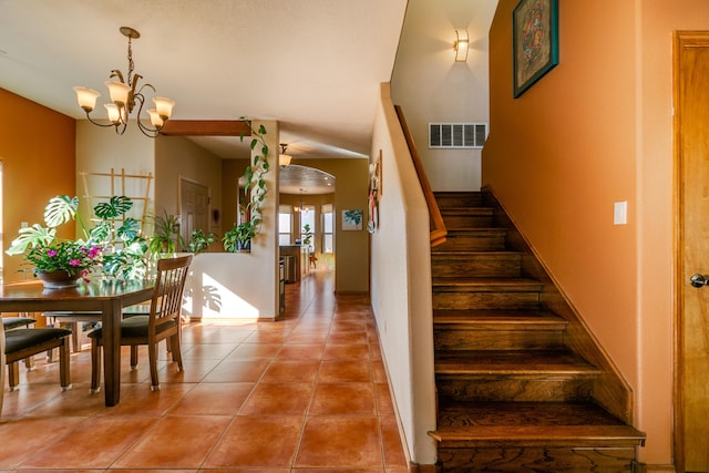 stairway with tile patterned floors and a chandelier