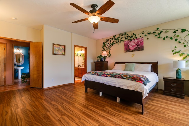 bedroom with hardwood / wood-style flooring, ceiling fan, and ensuite bath