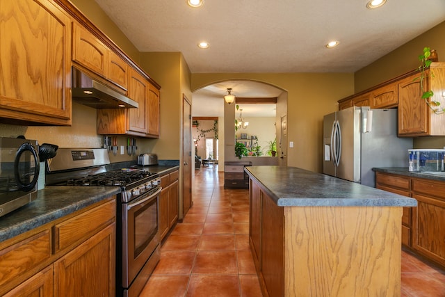 kitchen featuring a kitchen island, appliances with stainless steel finishes, light tile patterned floors, and an inviting chandelier