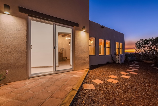 property exterior at dusk featuring a patio area and ac unit