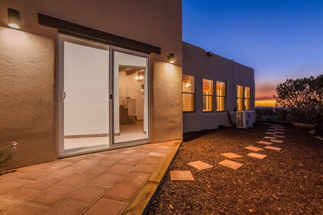 property exterior at dusk featuring a patio area and ac unit