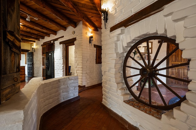 hallway featuring brick wall and beam ceiling