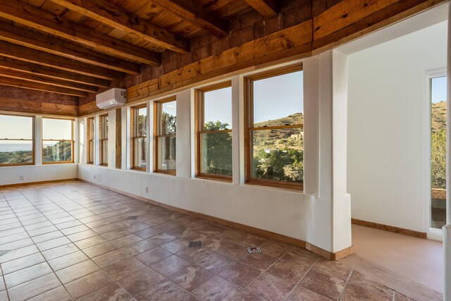 unfurnished sunroom with beamed ceiling, wood ceiling, plenty of natural light, and a wall mounted AC