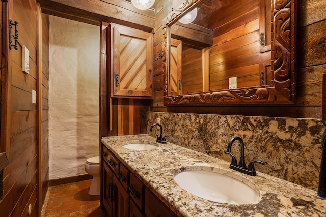 bathroom featuring wooden walls, vanity, and toilet