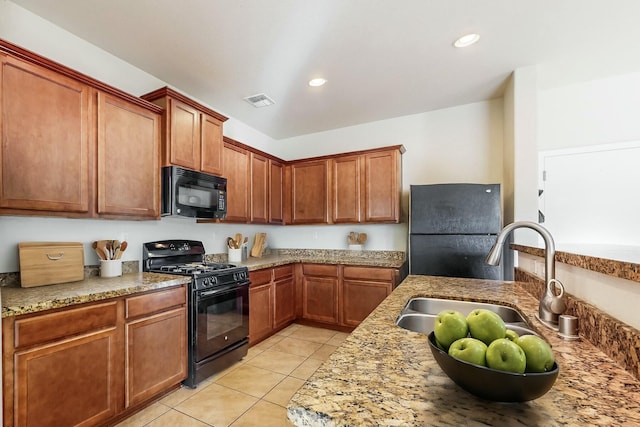 kitchen with light stone countertops, sink, light tile patterned floors, and black appliances