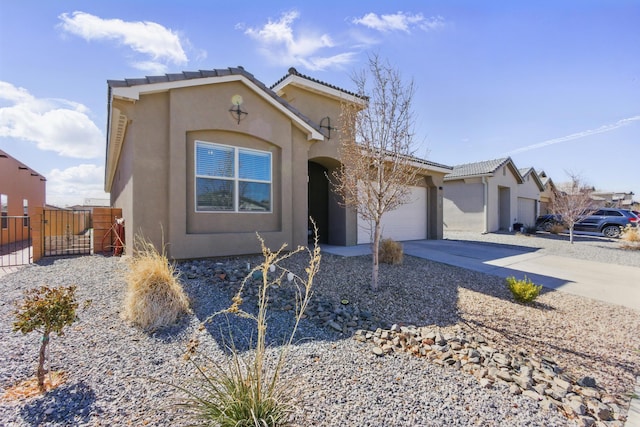 mediterranean / spanish-style house featuring stucco siding, driveway, a gate, fence, and a garage