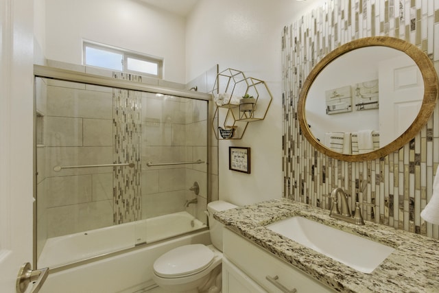 bathroom featuring enclosed tub / shower combo, toilet, and vanity