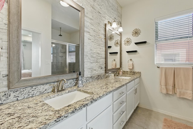 bathroom with a sink, a stall shower, double vanity, and tile patterned flooring