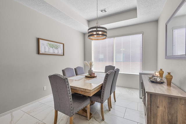 dining area featuring a notable chandelier, a raised ceiling, and a textured ceiling