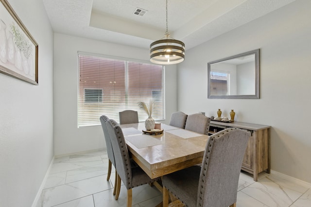 dining area featuring visible vents, baseboards, a tray ceiling, marble finish floor, and a textured ceiling