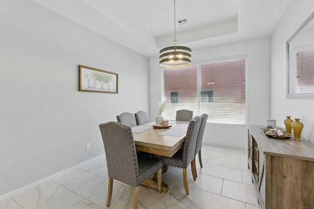 dining area with a tray ceiling, visible vents, marble finish floor, and baseboards