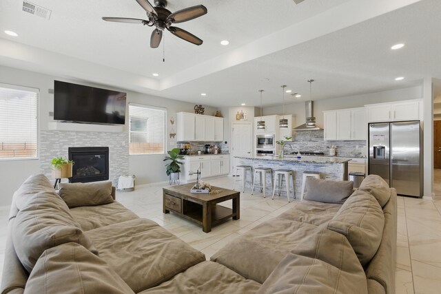 kitchen featuring wall chimney exhaust hood, sink, appliances with stainless steel finishes, light stone countertops, and white cabinets