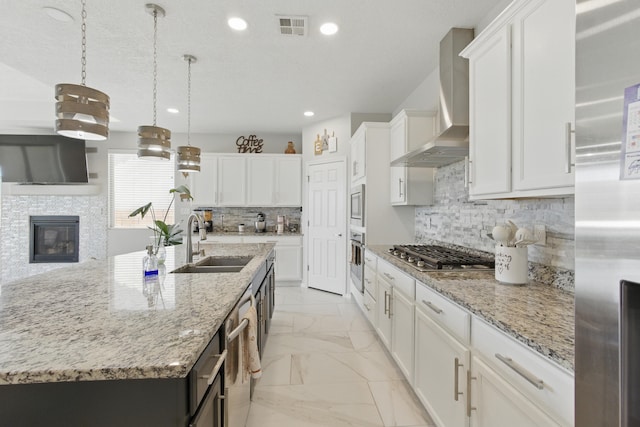 kitchen with visible vents, stainless steel appliances, a sink, wall chimney range hood, and marble finish floor