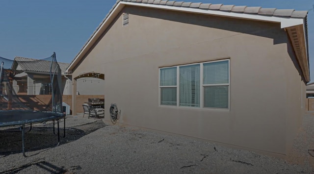 rear view of property with a trampoline and a patio area