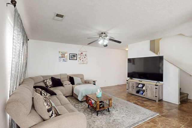 living room with a textured ceiling and ceiling fan